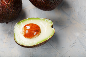 Sliced and whole organic Hass avocado on a gray background.