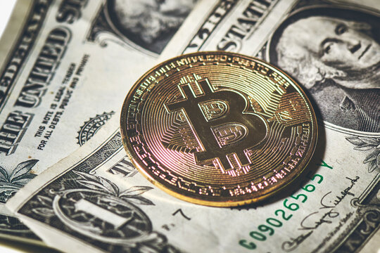 One bitcoin coin resting to paper dollars