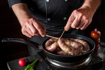 Close-up hands of chef tying a thread of homemade sausage. Cooking sausages with meat and spices on a pan. Working environment in the restaurant kitchen