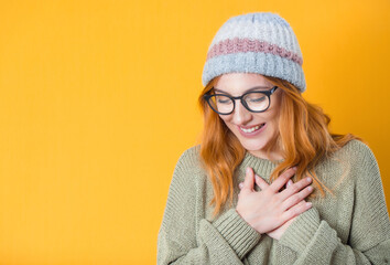 Grateful young woman looking down, isolated on yellow background. Thank you concept. Glad woman