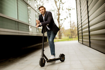 Young businessman using mobile phone  on electric scooter