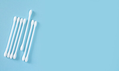 Flay lay of white plastic cotton sticks or swabs top view on blue background