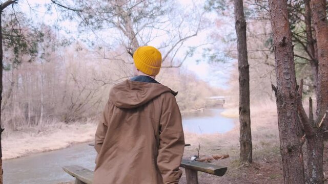 Backshot of a young traveller with yellow backpack walking in the forest. High quality 4k footage