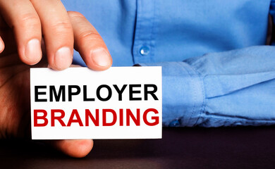 EMPLOYER BRADING is written on a white business card in a man's hand. Advertising concept