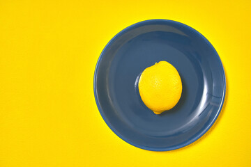 one yellow lemon on blue plate. copy space