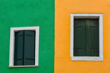 Fototapeta na wymiar Old walls of пкуут and orange with the windows closed shutters, Burano, Venice