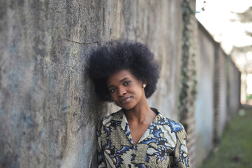 portrait of young black woman leaning against a wall