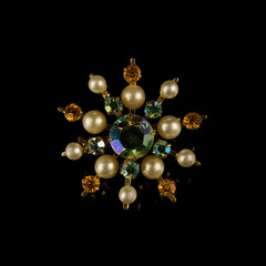 Round gold antique brooch with precious stones and crystals in the shape of a flower. Vintage brooch in the shape of a flower