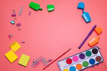 Stationery items on the pink background with free space for text. Creative, colorful background with scool supplies. Flatlay with copy space, top view. Markers, paper clips, sticky notes, watercolor.
