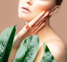 Lips, face beauty partial portrait of model woman with green leaf, perfect skin, bright nail manicure
