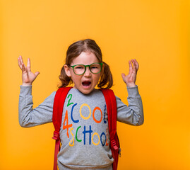 Pupil girl is angry very much. Crazy and mad shouting kid isolated on yellow background. and yelling with aggressive expression and arms raised. Frustration concept.