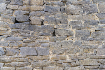 The wall is made of stone. Close-up. The old stone masonry of the monastery fence. Stone wall texture (Ural, Russia)