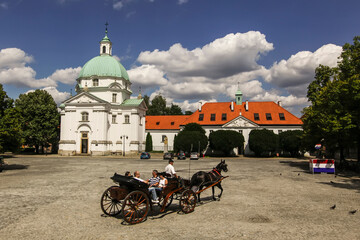 Naklejka na ściany i meble Tourist horse-drawn carriage on New Town Market with Benedictine Monastery in Warsaw, Poland. June 2012