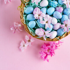 Fototapeta na wymiar Wicker basket with chocolat eggs and spring bright flowers, selective focus