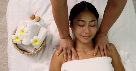 Young Asian woman receiving a shoulder massage at spa salon by professional masseuse, Spa treatment and thai massage concept