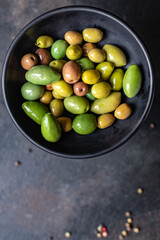 pitted olives in a plate on the table different varieties of fruits  vegan or vegetarian food keto or paleo diet snack trend meal copy space food background rustic. top view 