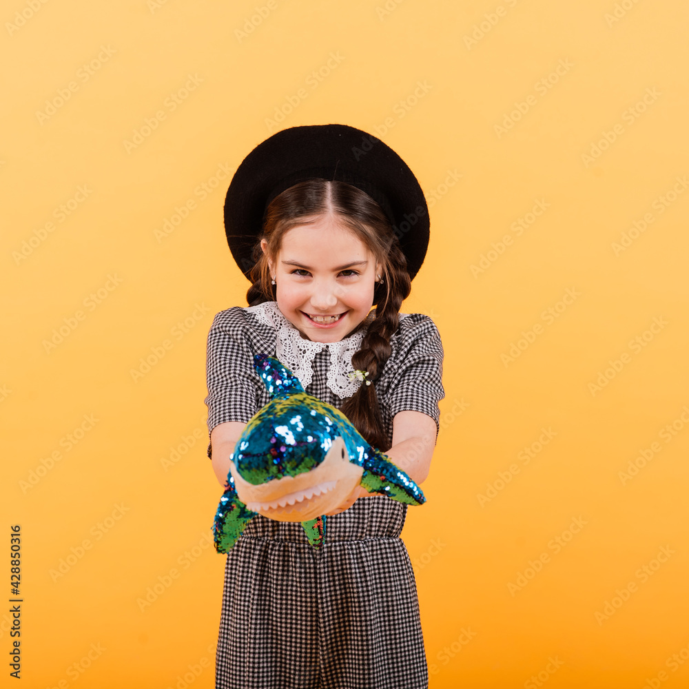 Wall mural young girl playing with plush shark toy in yellow studio