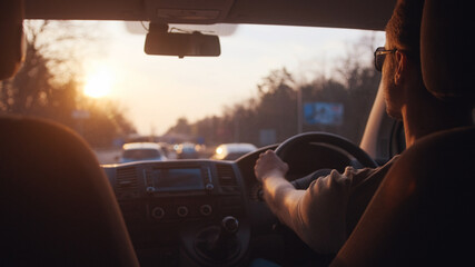 The young man driving the car along the city highway
