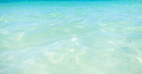 Blue and bright and clear water surface and ripple wave with sun reflection in the sea. close up sea wave, low angle view.