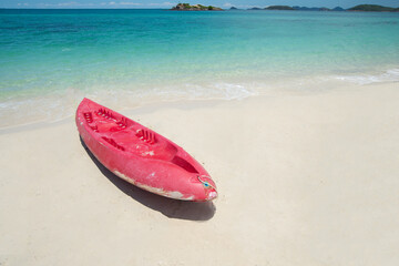 Red Kayak at the tropical beach at beautiful Clear day. Beautiful clear sand beach and tropical light blue sea. Soft wave blue ocean on sandy beach. Sallow water, Clear water. Seaside. Copy space.