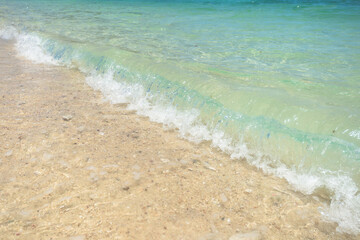 Beautiful clear sand beach and tropical light blue sea. Soft wave of blue ocean on sandy beach. Sallow water, Clear water. Seaside.