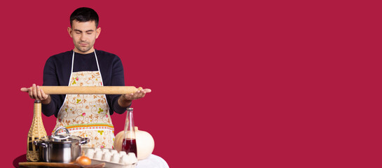Banner, long format on red background. Home kitchen or small restaurant, male chief cook concept. Young man meditating and creating ideas for cooking recipe . Professional development