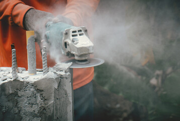 Professional plasterers are using electric cutters to cut around the cement pillars to build walls.