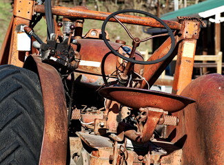 Close up on an old rusty tractor sitting in an orchard.
