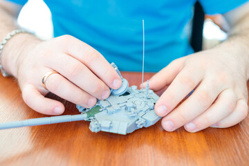 a man assembles a plastic tank model toy, assembles a tank turret