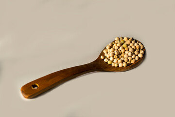 Yellow peas on a wooden spoon on a gray background, natural lighting of peas and spoons of evening rays of the sun.