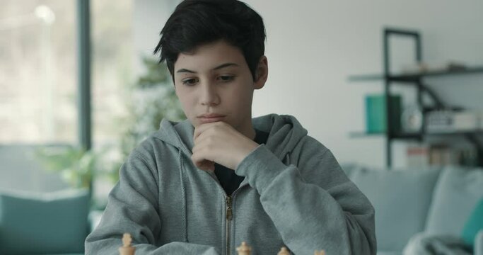 Boy playing chess and looking at the chessboard