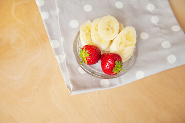 strawberry and banana on a glass plate on a wooden background