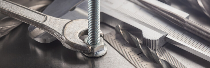 Wrench tightens nut in steel billet with ruler and caliper. Spanner, bolt, screw and nuts.