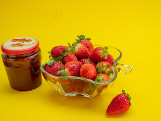 strawberries and a jar of jam on a yellow background