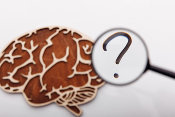 Wooden brain with question sign and magnifier. Human doubt
