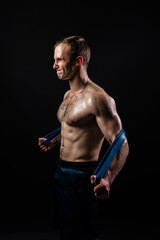 Fototapeta na wymiar Man on black background keeps dumbbells pumped up in fitness active chest black, athlete muscular workout athletic healthy pectoral. handsome adult, gym fit With a ribbon in hand, the fitness gum is