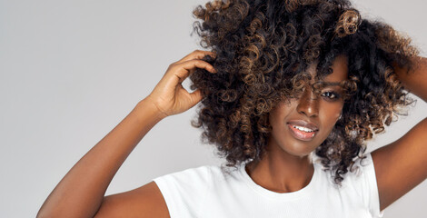 Sexy black woman playing with her afro hair isolated on gray background - obrazy, fototapety, plakaty