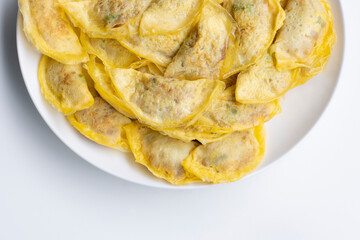 Top view of egg wrapped dumplings (also known as omelette dumplings) with pork filling on a white plate isolated on white.