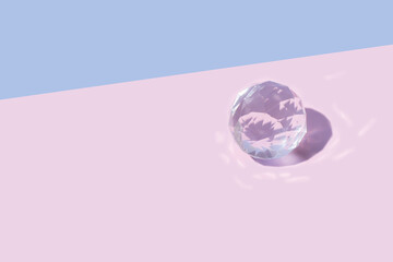 Luminous bright crystal glass transparent ball against pastel pink background. Minimal bauble rolls creative concept.