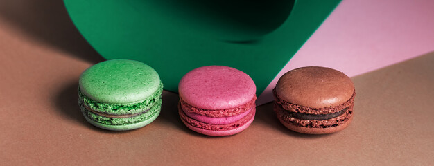 French macarons on a multicolored paper background with place for text. Pastry chef app with copy space. Creative concept Banner 