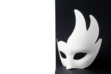 White carnival mask on a black and white background. The mask stands on a black background. - obrazy, fototapety, plakaty