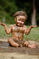 Fototapeta na wymiar Criança brincando na lama linda com sorriso perfeito.