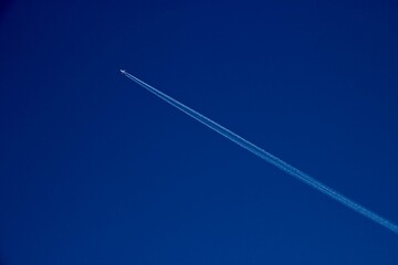 flying plane with an inversion track on a blue sky background