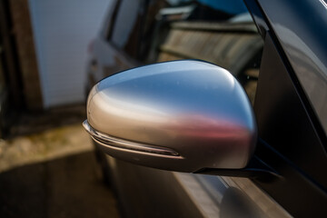 Off side wing mirror of a grey Suzuki motor vehicle with intentional shallow depth of field and...