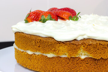 Cream tart with strawberries and lemon sponge cake on white plate