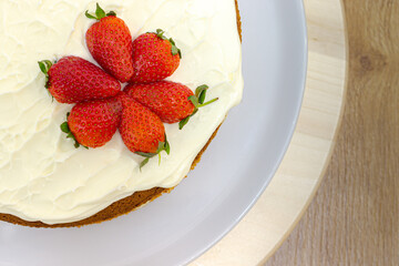 Cream tart with strawberries and lemon sponge cake on white plate