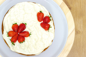 Cream tart with strawberries and lemon sponge cake on white plate