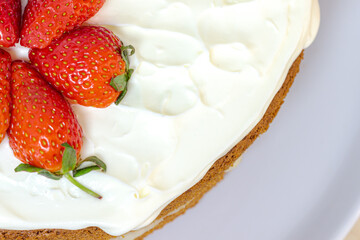 Cream tart with strawberries and lemon sponge cake on white plate