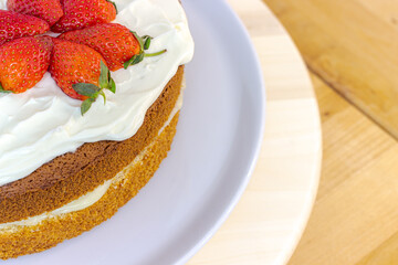 Cream tart with strawberries and lemon sponge cake on white plate