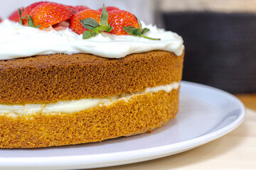 Cream tart with strawberries and lemon sponge cake on white plate